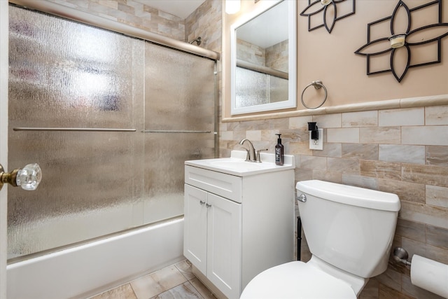 full bathroom with tile walls, vanity, enclosed tub / shower combo, and toilet