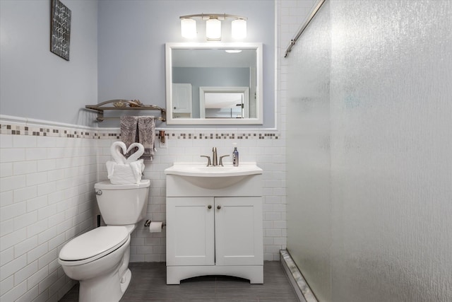 bathroom featuring vanity, toilet, and tile walls