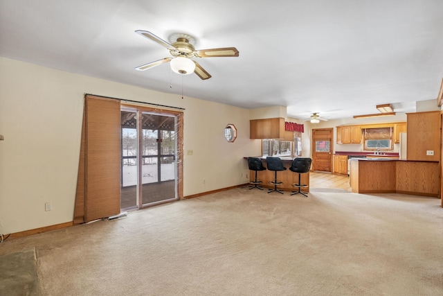 unfurnished living room with light carpet, sink, and ceiling fan