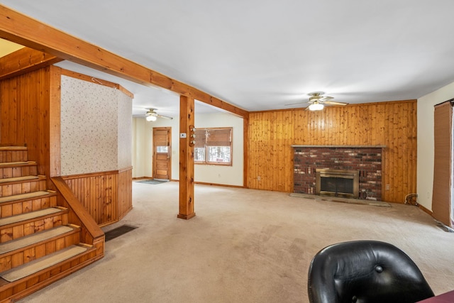 carpeted living room featuring beam ceiling, ceiling fan, a fireplace, and wood walls