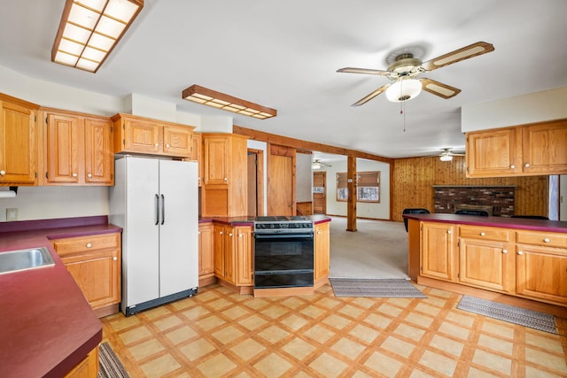 kitchen featuring range with gas cooktop, wood walls, white refrigerator, ceiling fan, and a fireplace