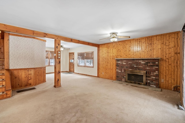 living room featuring wooden walls, light colored carpet, a fireplace, and ceiling fan