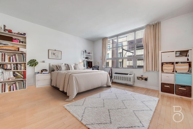 bedroom with hardwood / wood-style flooring and a wall unit AC