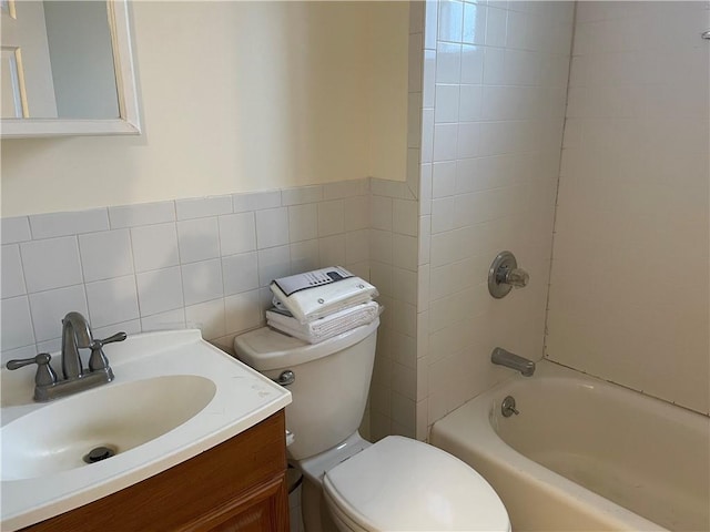 full bathroom featuring vanity, tiled shower / bath, tile walls, and toilet