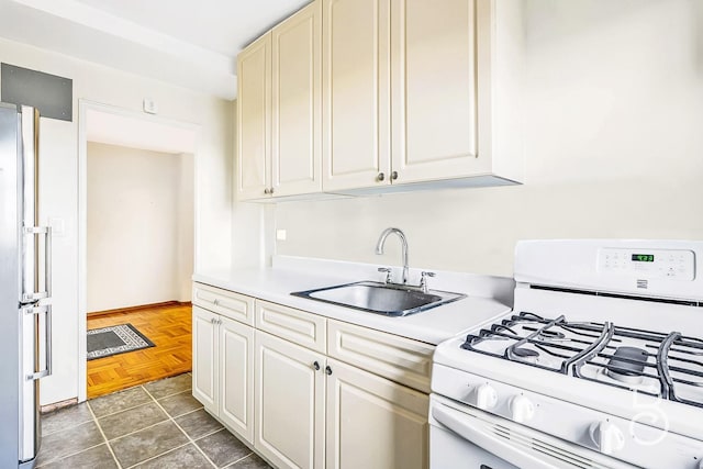 kitchen featuring white gas range, dark parquet flooring, sink, and stainless steel fridge