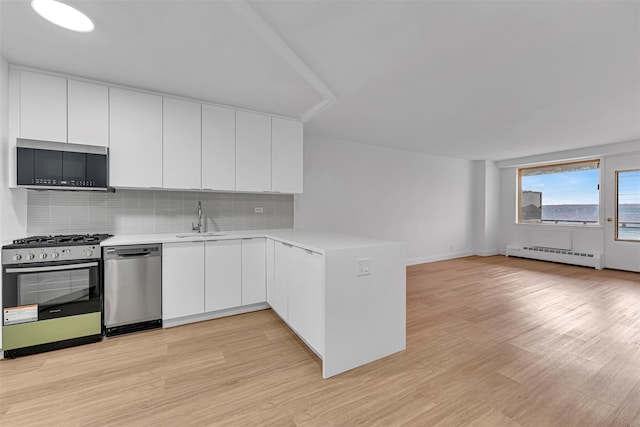 kitchen featuring sink, a baseboard radiator, kitchen peninsula, stainless steel appliances, and white cabinets