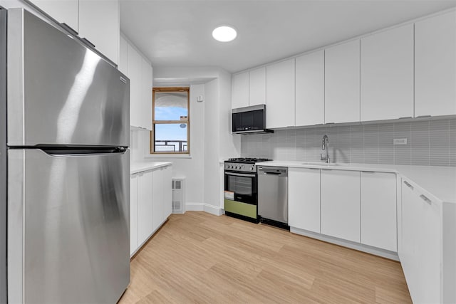 kitchen featuring stainless steel appliances, white cabinetry, sink, and light wood-type flooring