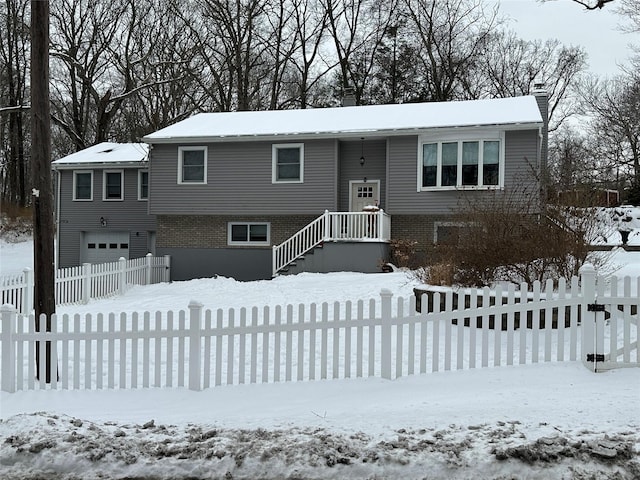 raised ranch with an attached garage, a chimney, and brick siding