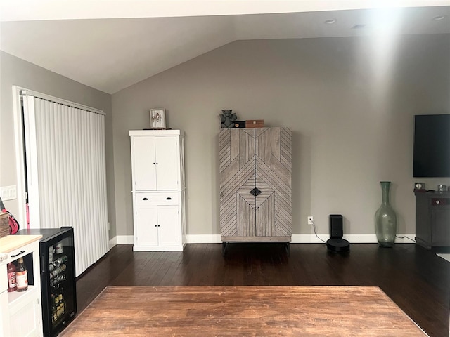 interior space with lofted ceiling, wine cooler, baseboards, and dark wood-style flooring