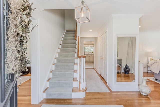 staircase with crown molding and hardwood / wood-style floors