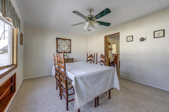 carpeted dining area featuring crown molding and ceiling fan