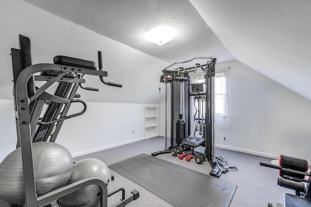 exercise room with vaulted ceiling and carpet