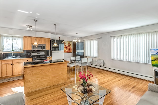 kitchen with appliances with stainless steel finishes, decorative light fixtures, a baseboard radiator, a chandelier, and light wood-type flooring