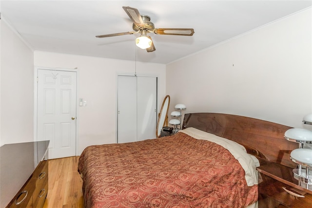 bedroom with ceiling fan, ornamental molding, wood-type flooring, and a closet