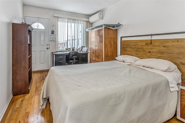 bedroom featuring a wall mounted air conditioner and light wood-type flooring