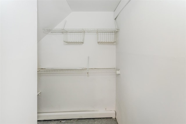 spacious closet featuring a baseboard radiator and lofted ceiling