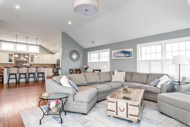 living area featuring high vaulted ceiling, light wood-type flooring, visible vents, and recessed lighting