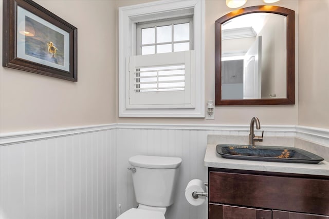 half bathroom featuring wainscoting, vanity, and toilet