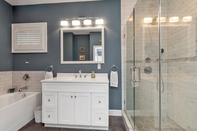 bathroom with a stall shower, a garden tub, vanity, and baseboards