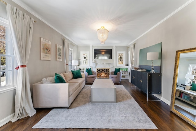 living room featuring dark wood-type flooring, a healthy amount of sunlight, ornamental molding, and baseboards