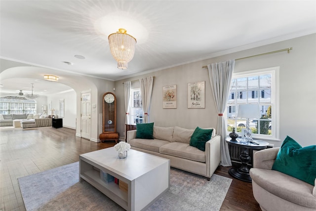 living room featuring arched walkways, crown molding, wood finished floors, and a notable chandelier