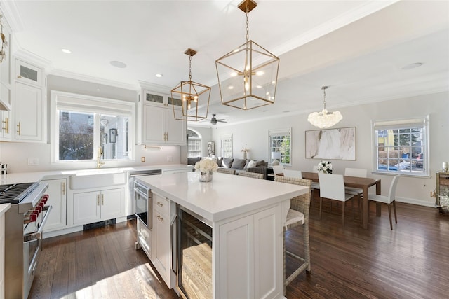 kitchen with wine cooler, a center island, high end stainless steel range oven, white cabinetry, and a sink