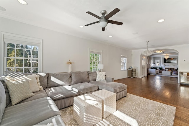 living area featuring arched walkways, recessed lighting, wood finished floors, a ceiling fan, and crown molding