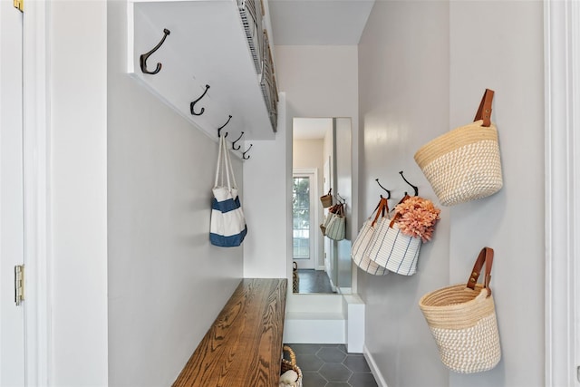 mudroom with dark tile patterned flooring and baseboards