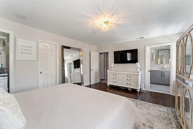 bedroom with visible vents, dark wood-type flooring, connected bathroom, a sink, and baseboards