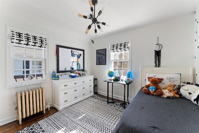 bedroom with radiator, baseboards, and wood finished floors