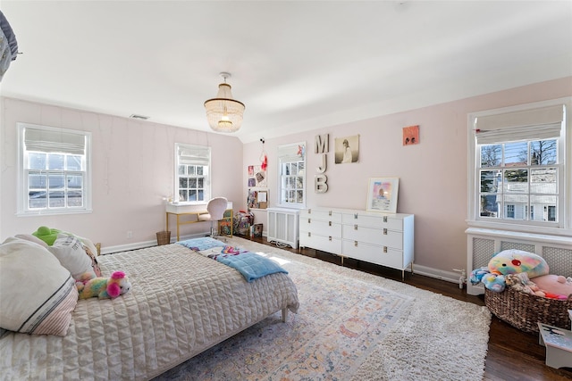 bedroom featuring baseboards, visible vents, radiator heating unit, and wood finished floors