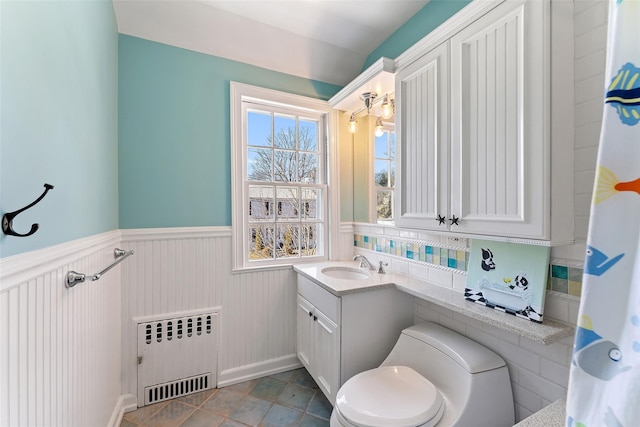 bathroom with wainscoting, radiator, toilet, tile patterned floors, and vanity