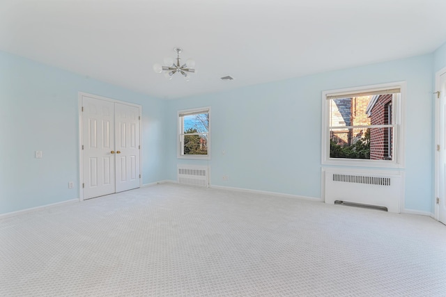 182-61 Avon Rd, Jamaica Estates, NY 11432 - carpeted spare room featuring a notable chandelier, radiator heating unit, and a wealth of natural light