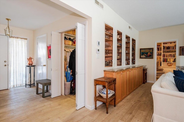 corridor featuring light wood-style flooring and visible vents