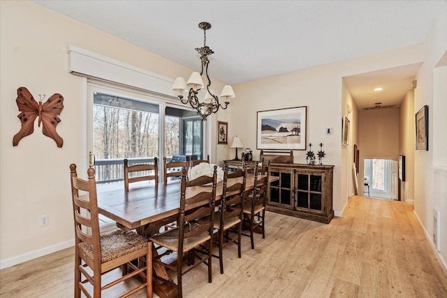 dining area featuring light wood finished floors, plenty of natural light, baseboards, and an inviting chandelier