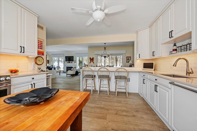 kitchen featuring white cabinets, open floor plan, light countertops, pendant lighting, and a sink