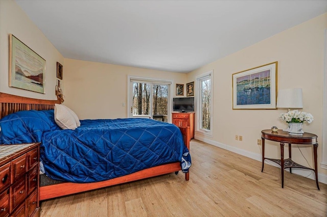 bedroom featuring access to outside, light wood finished floors, and baseboards