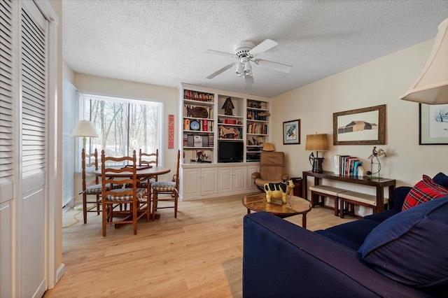 living area with light wood finished floors, a textured ceiling, and a ceiling fan