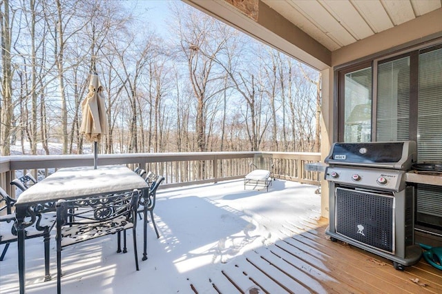 snow covered deck with outdoor dining space and area for grilling