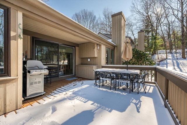 snow covered deck with grilling area and outdoor dining space