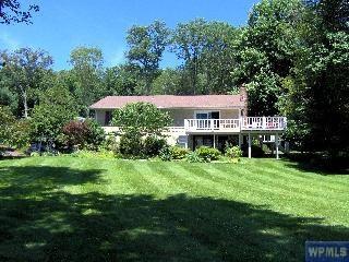 back of property with a wooden deck and a lawn