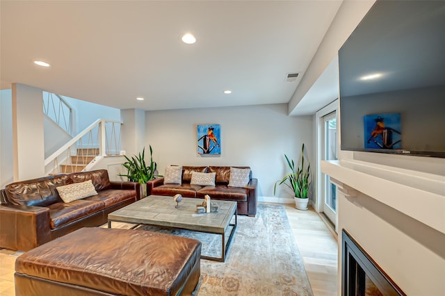 living area featuring visible vents, baseboards, stairs, light wood-style floors, and recessed lighting