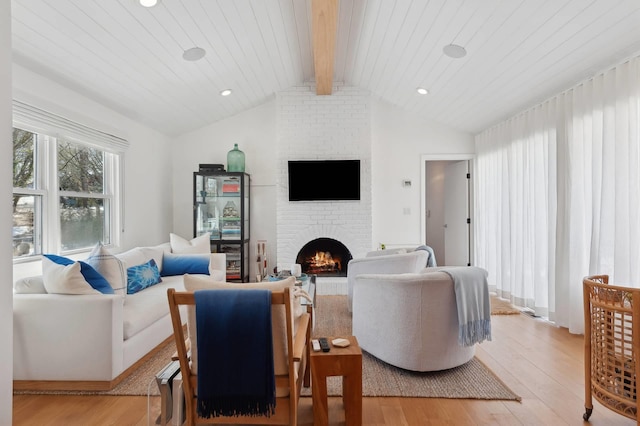 living room with vaulted ceiling with beams, recessed lighting, a fireplace, and light wood-style floors