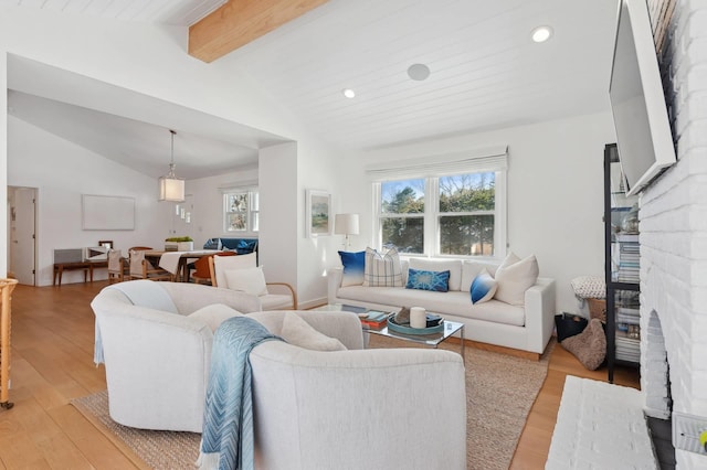 living area featuring vaulted ceiling with beams, light wood-style flooring, a fireplace, and recessed lighting