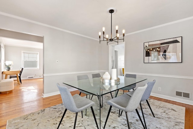 dining room featuring visible vents, crown molding, light wood-style flooring, and baseboards