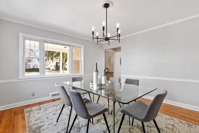 dining space featuring light wood-style flooring, visible vents, baseboards, an inviting chandelier, and crown molding