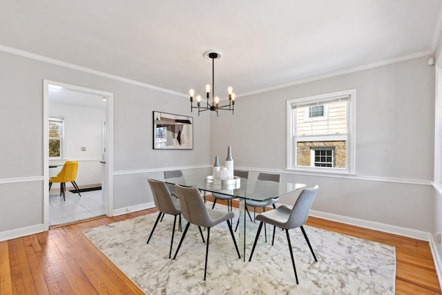 dining room with light wood-style floors, crown molding, and baseboards