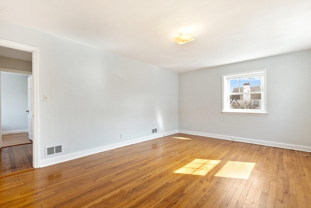 empty room featuring baseboards, visible vents, and wood finished floors