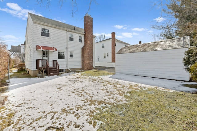 snow covered back of property with a chimney