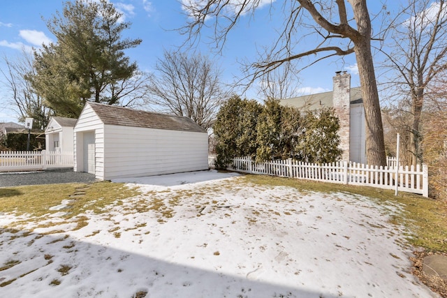 snow covered garage featuring a detached garage and fence